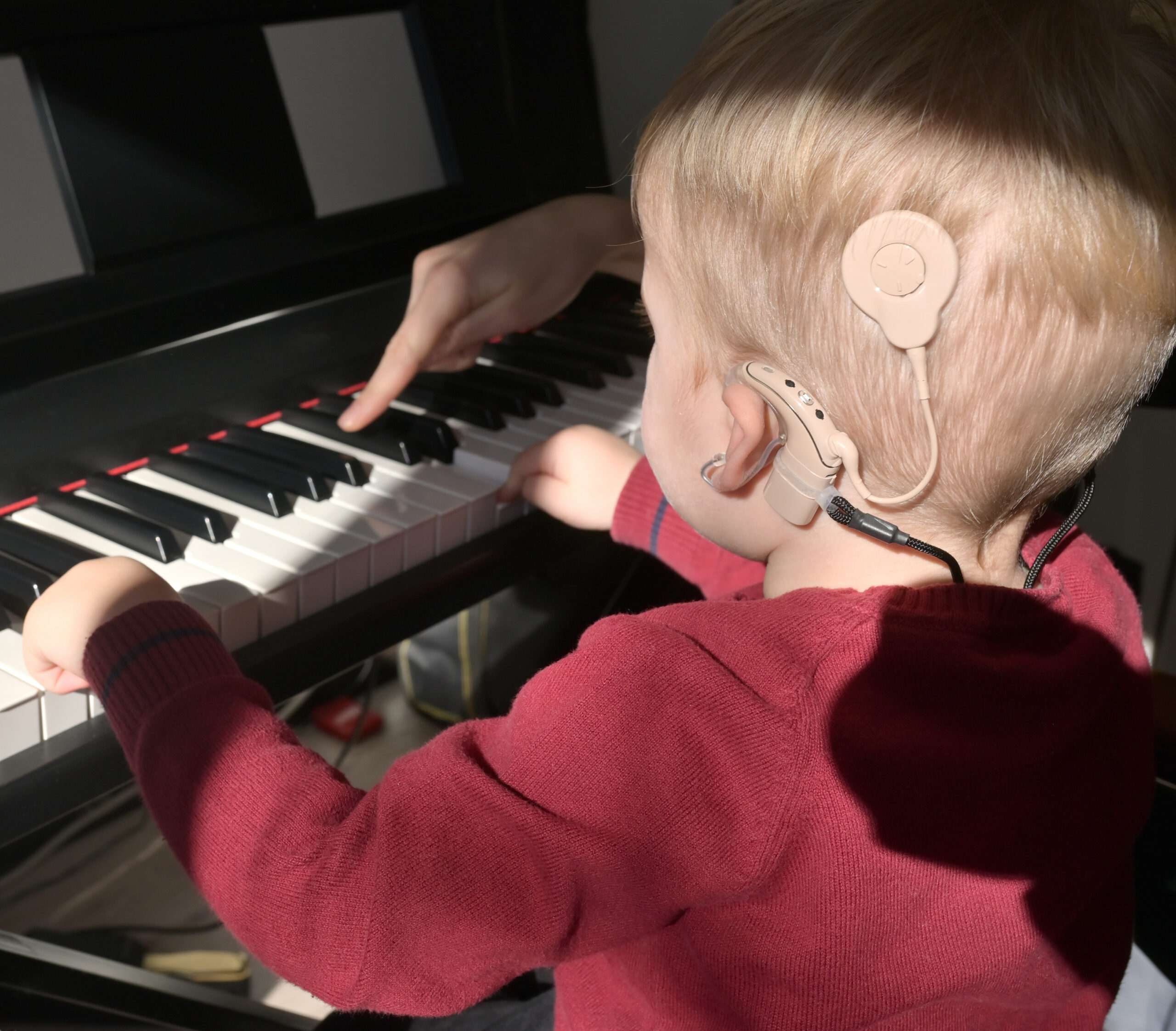 Hearing Implants NHS, child learning to play piano